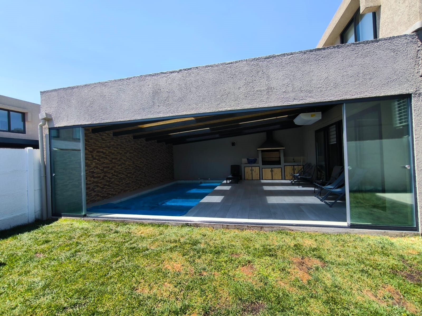 Ampliación techada con estructura metálica vista desde el jardín