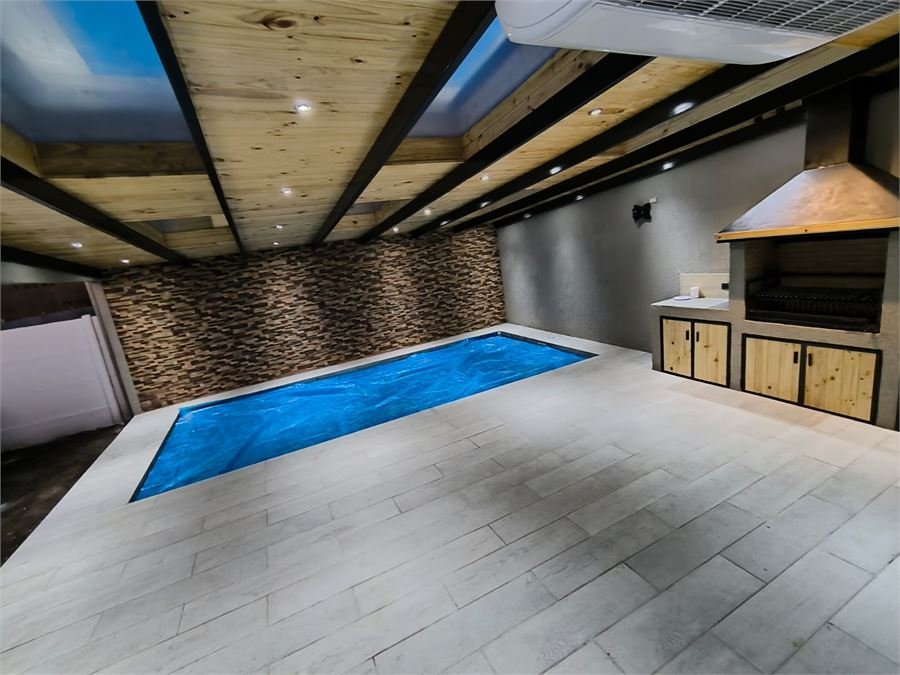 Piscina interior terminada con pavimento porcelanato y cielo de madera