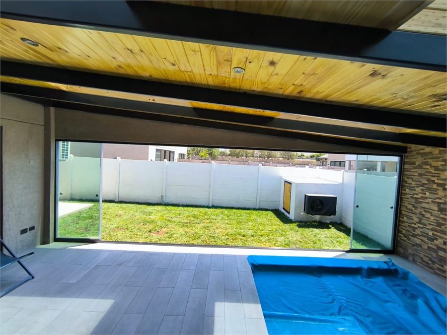 Espacio techado con estructura metálica y gran vano de salida al jardín